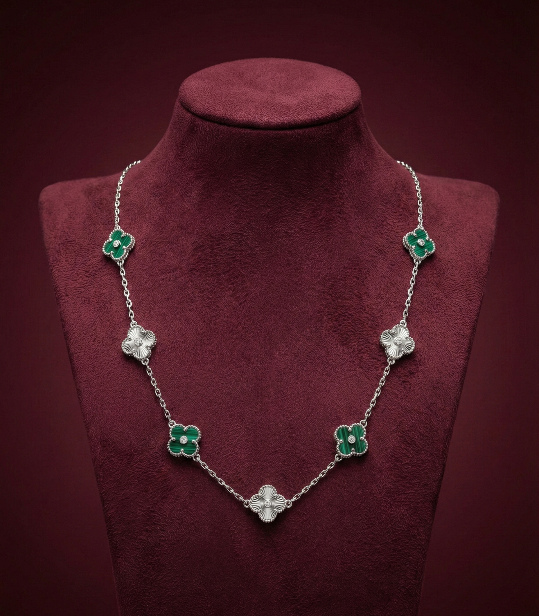 Necklace with green and clear floral pendants on a red velvet stand