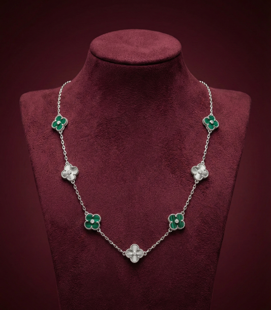 Necklace with green and clear floral pendants on a red velvet stand