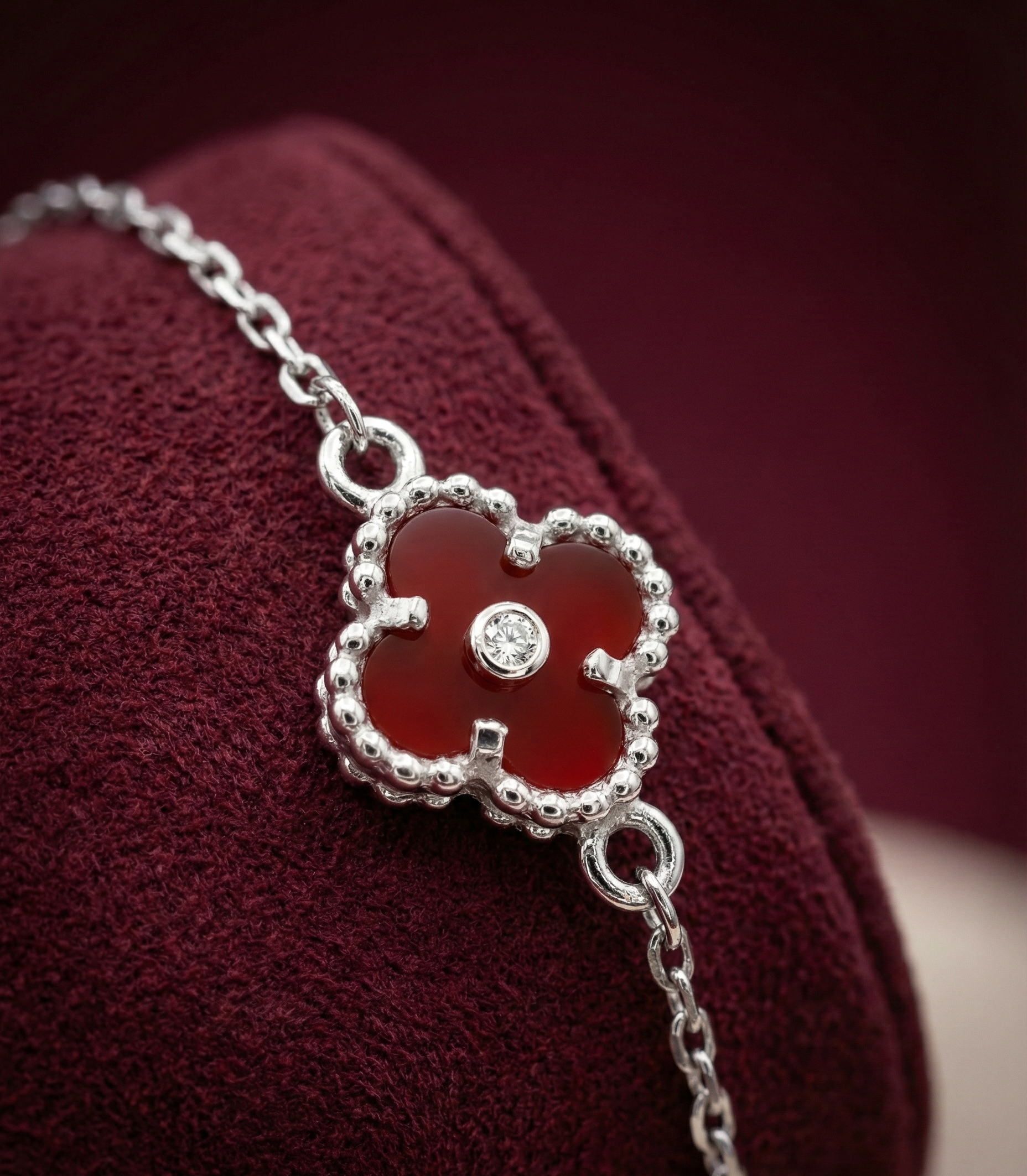 Silver bracelet with a red flower-shaped clasp on a burgundy background
